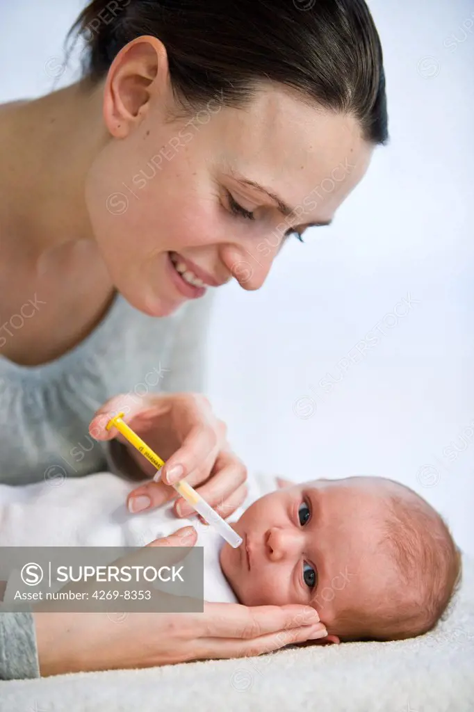 Mother giving her one month old baby vitamin D with a pipette.