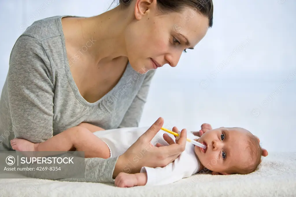 Mother giving her one month old baby vitamin D with a pipette.