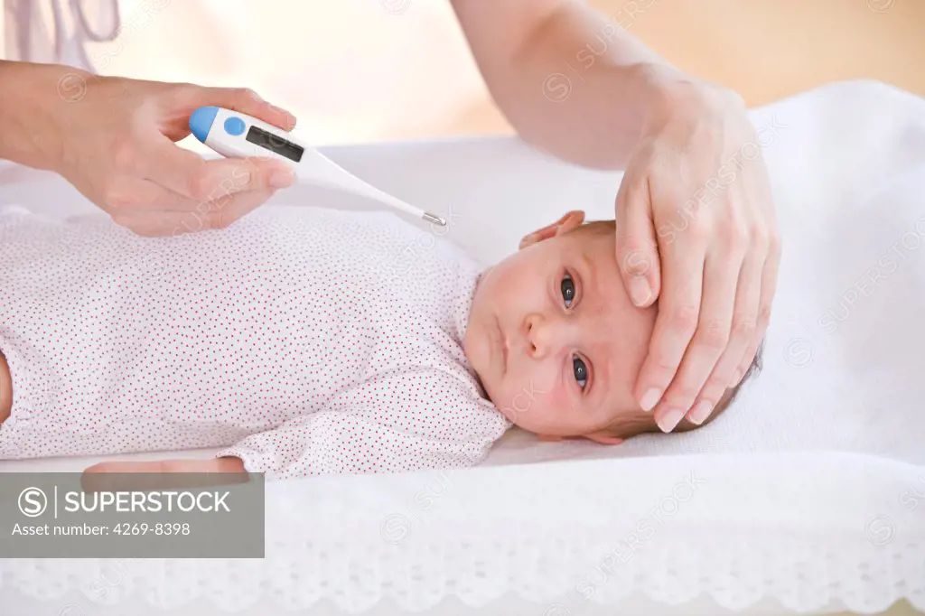 Mother checking the temperature of her 2 months old feverish baby with a digital thermometer.