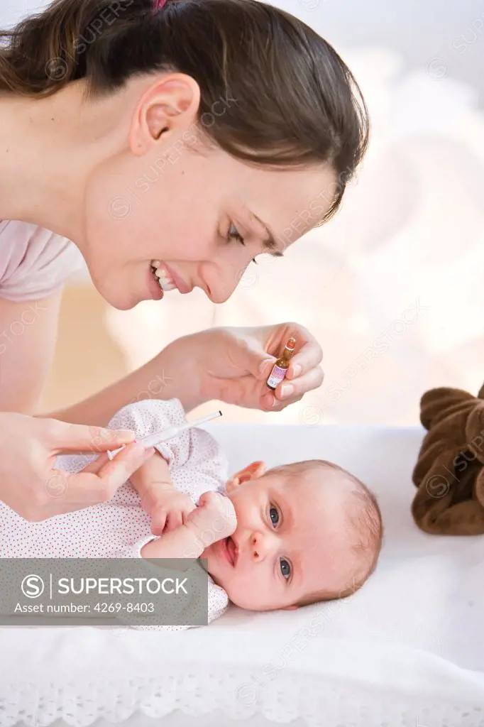Mother giving her 2 months old baby vitamin K with a pipette.