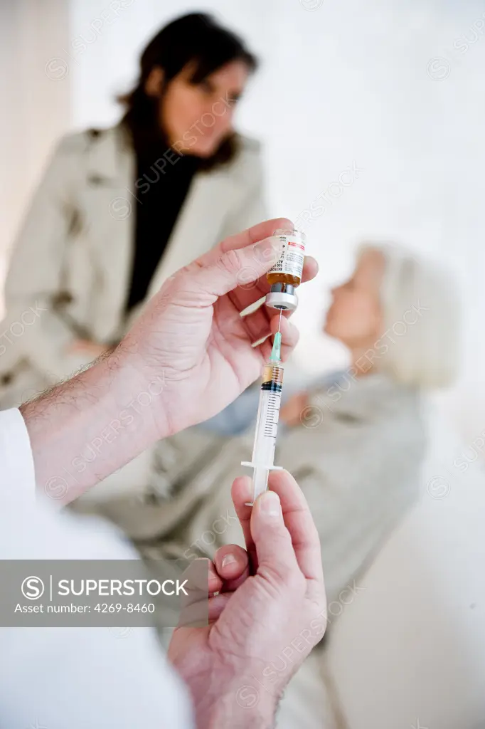 Doctor preparing injection for elderly woman.