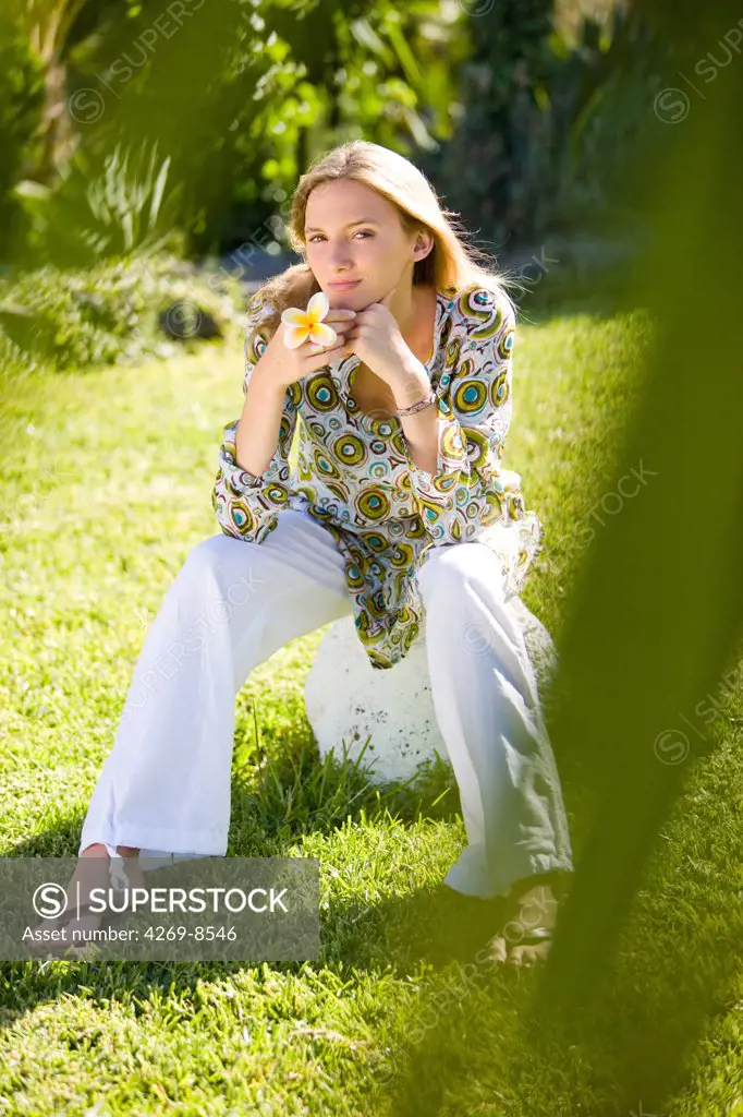 Portrait of young woman sitting in garden.