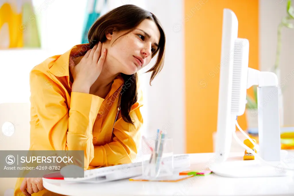 Woman suffering from neck pain in office.