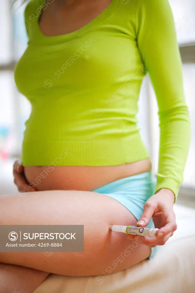 Pregnant woman giving herself an insulin injection with an insulin pen to treat diabetes.