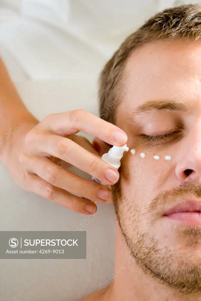 Man receiving an anti-wrinkle or anti-pocket cream around the eyes.