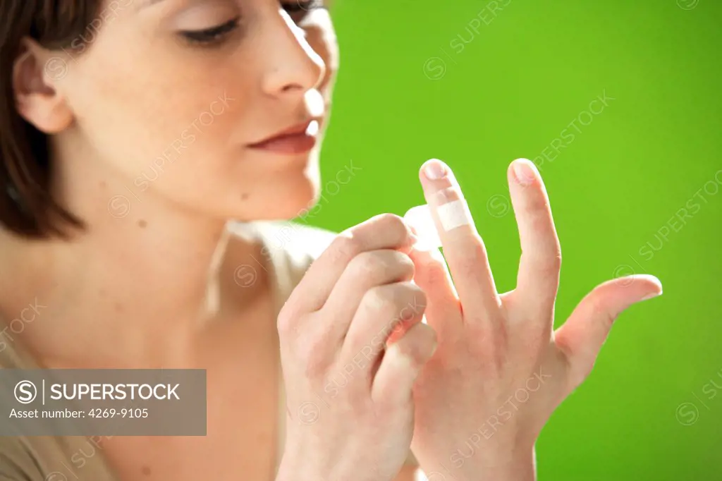 Woman putting a band-aid on her finger.