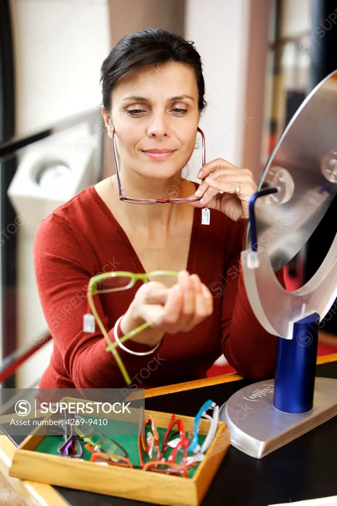 Woman trying on prescription glasses in opticians.