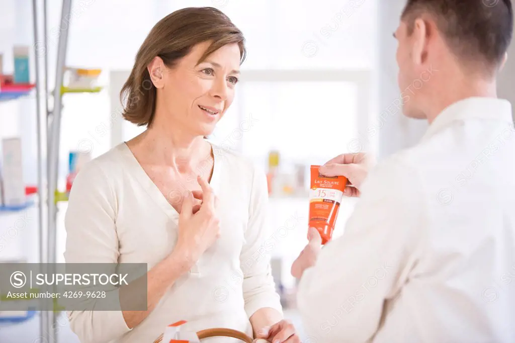 Pharmacist showing a customer sunscreen.