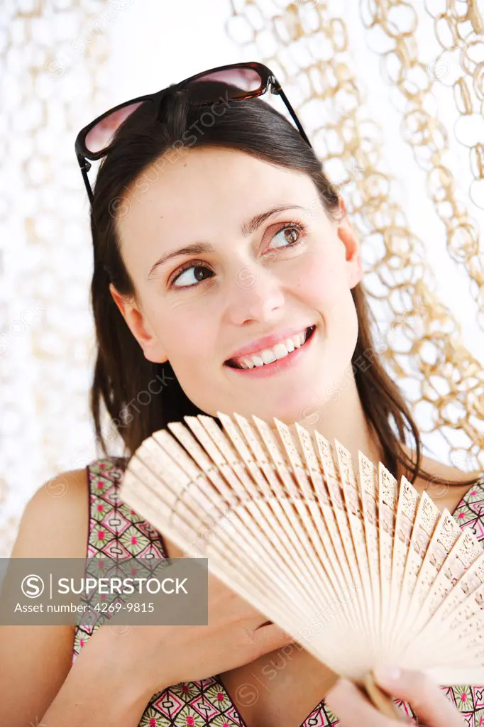 Woman cooling her face with a fan.