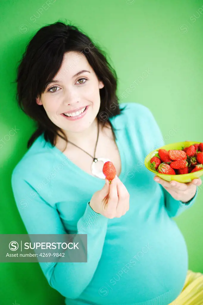 Pregnant woman eating strawberries. During pregnancy a balanced and nutritious diet is recommended, including fruit rich in vitamins.