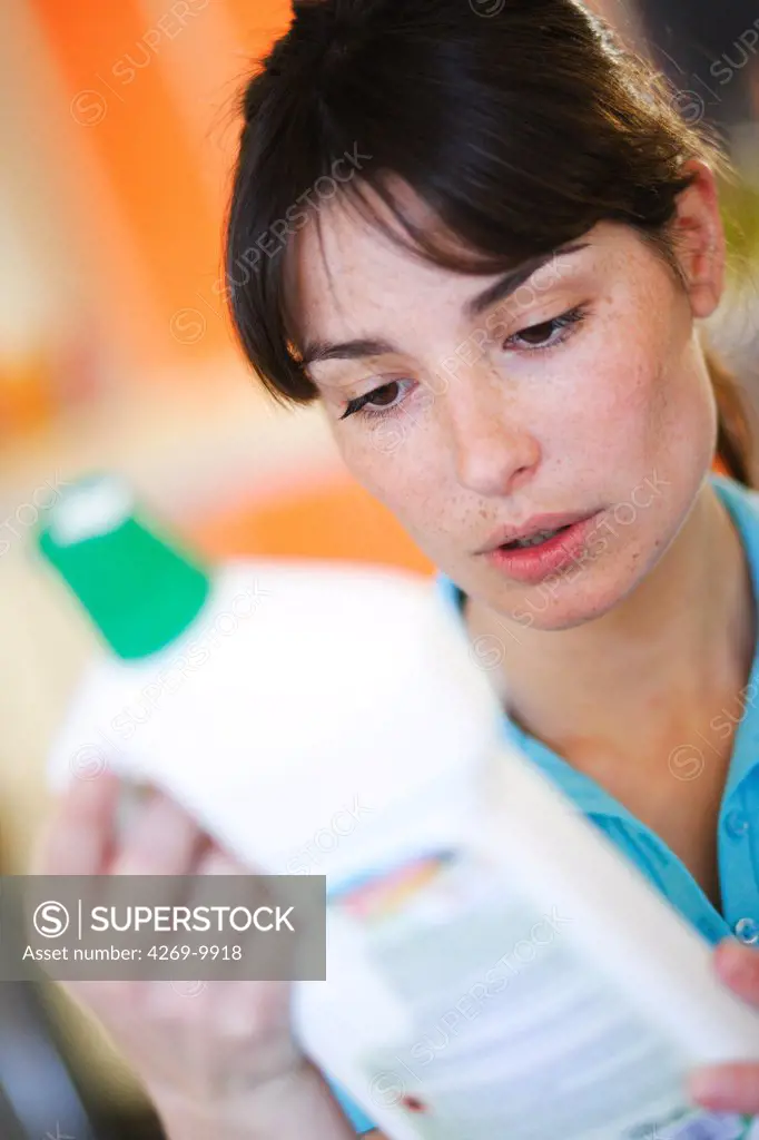 Woman reading the composition of cleaning product.