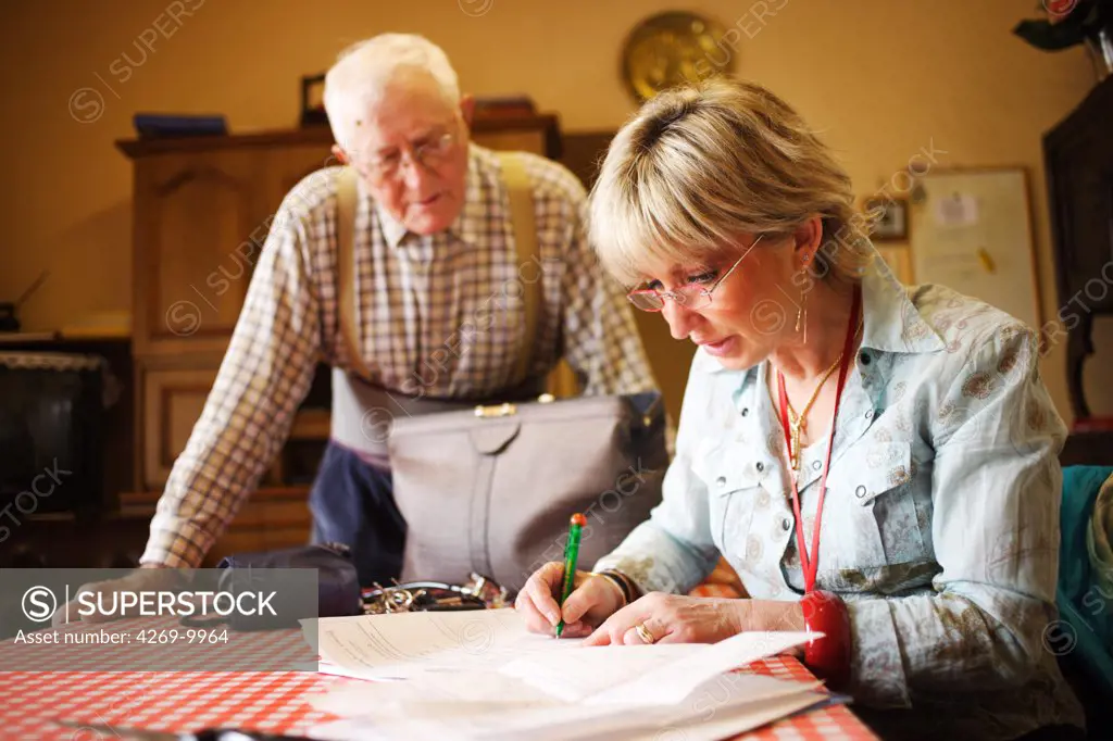 General practitioner writing a medical prescription during home visit.