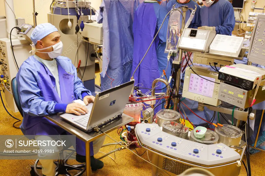 Anaesthesist at work during mitral valve replacement surgery, an open heart surgery requiring a cardiopulmonary bypass. Thoracic and Cardiovascular Surgery Department, Limoges hospital, France.