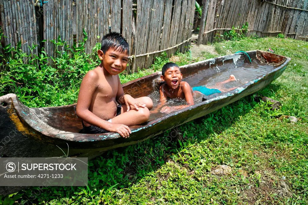 Panama, Kuna Yala, Indigenous Guna boys take bath in wooden boat filled with water