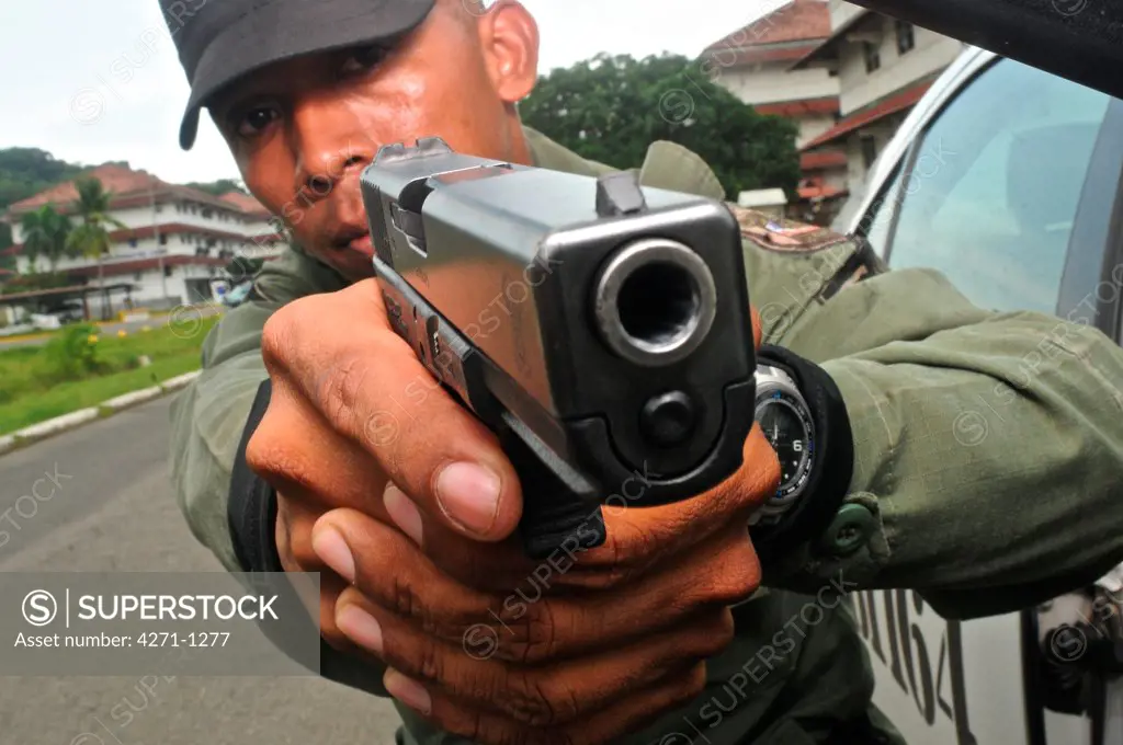 Uniformed police officer aiming a pistol at a tactical and firearms training course at the Panamanian National Police force academy, Panama