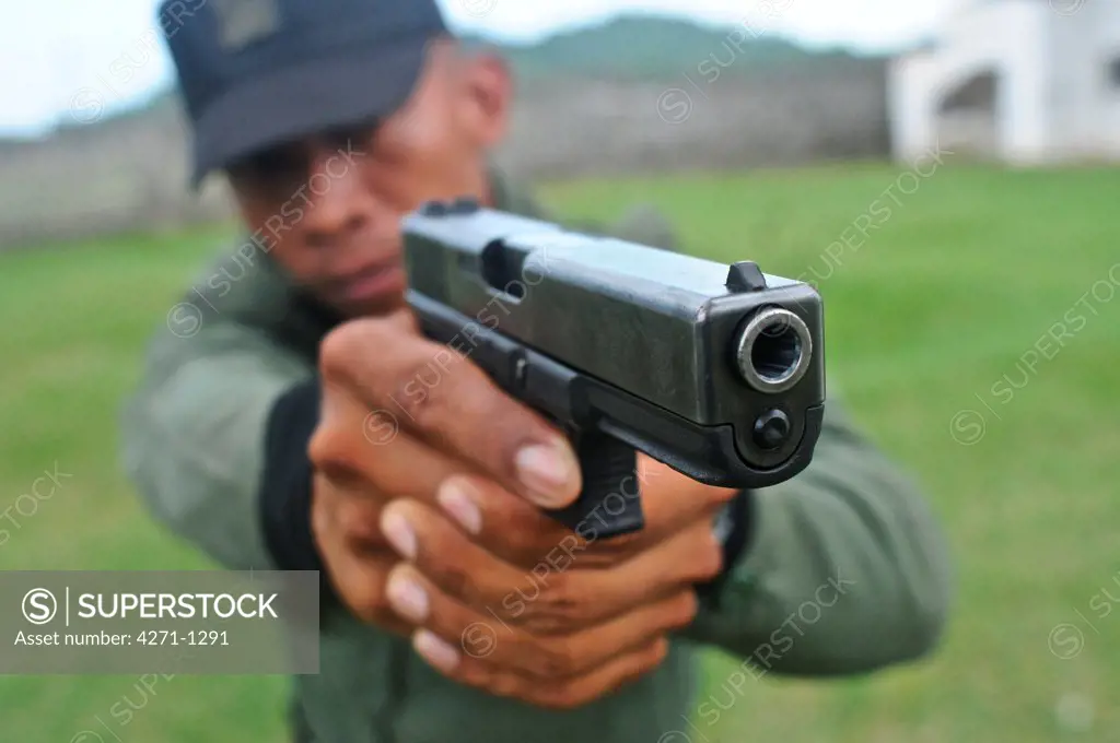 Uniformed police officer aiming a pistol at a tactical and firearms training course at the Panamanian National Police force academy, Panama