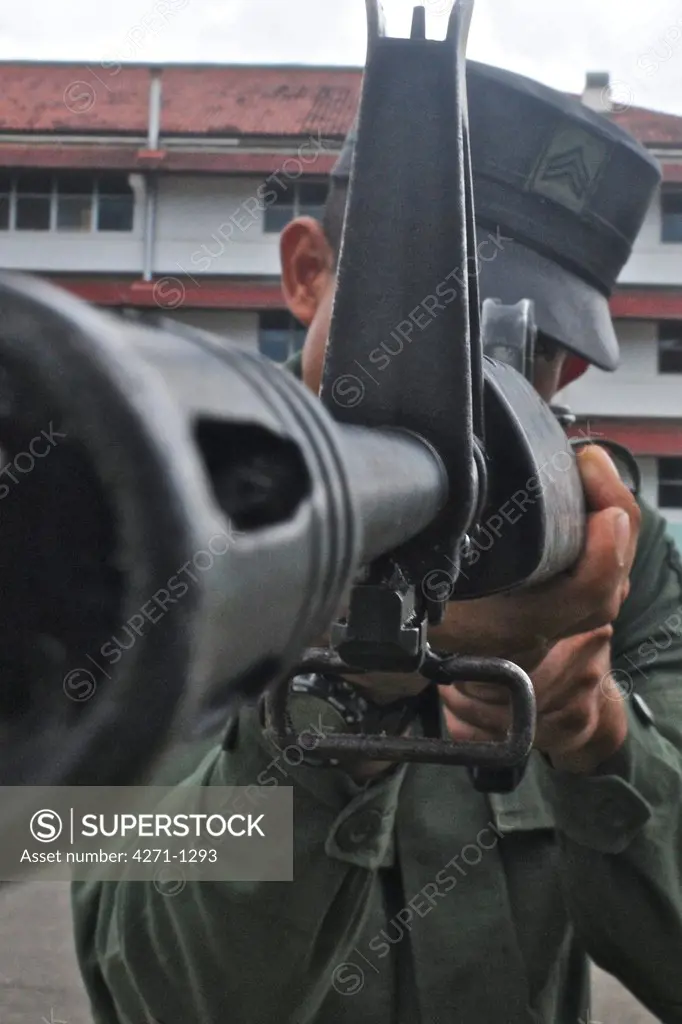 Uniformed police officer aiming an assault rifle at a tactical and firearms training course at the Panamanian National Police force academy, Panama