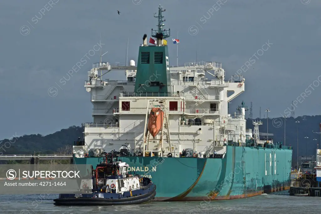 Panama Canal, Cargo ship passing canal being pulled by tugboat