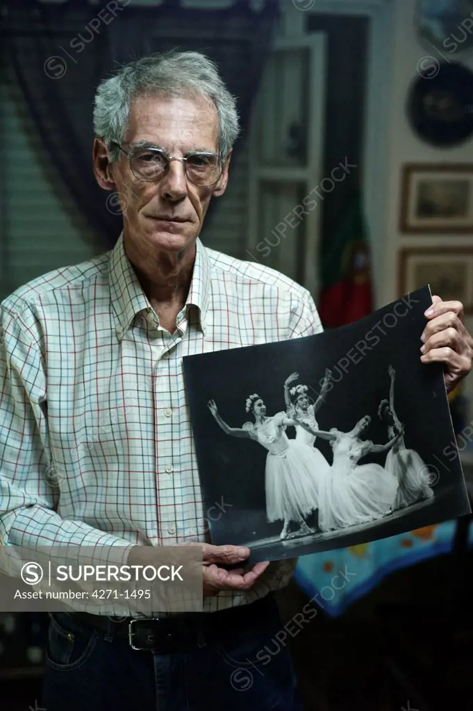 Cuba, Havana, Photographer holding one of his works with ballet dancers standing at home