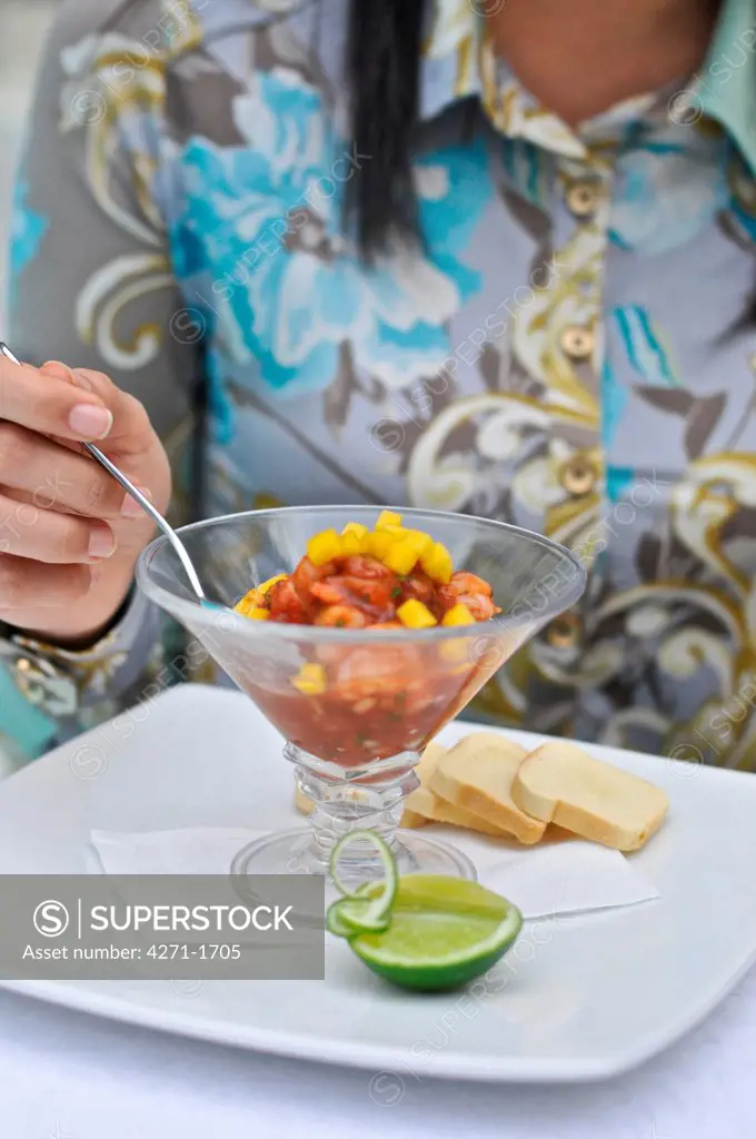 Colombia, Cali,  Young woman eating  shrimp appetizer near  hotel pool