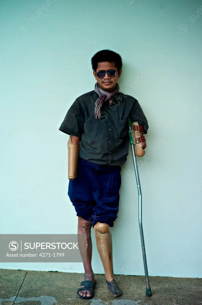 Portrait of a Cambodian land mine survivor lost both eyes and a leg and both arms now using a prosthetic rudimentary wooden limbs, Luang Phabang, Laos