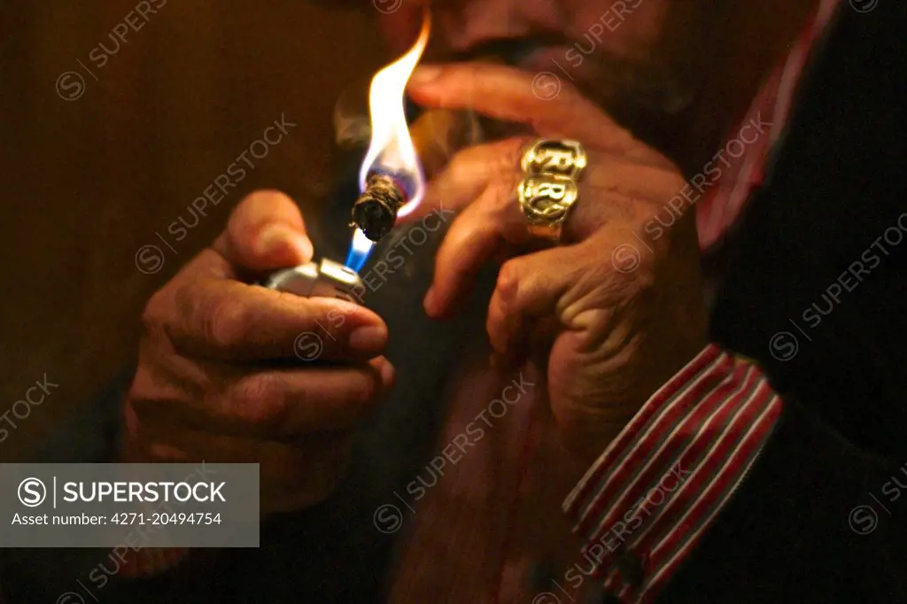 Cigar maker Carlos Robaina lighting a cigar.