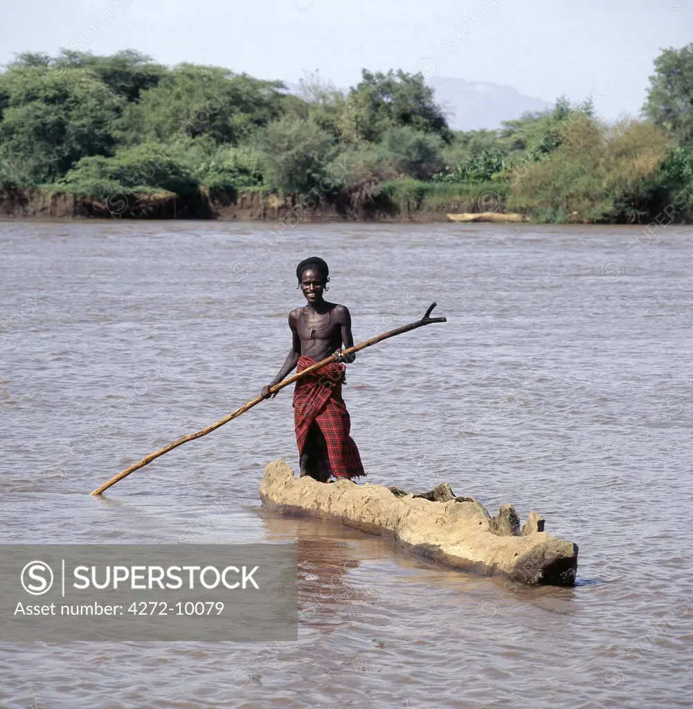 A Dassanech man poles a dug-out canoe across the muddy waters of a tributary of the Omo River in its delta near Lake Turkana.  The Omo has one of the largest inland deltas in the world and is home to a large section of Dassanech people who speak a language of Eastern Cushitic origin.
