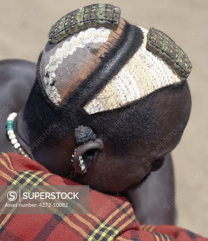 A finely decorated clay hairstyle of the Dassanech people of the Omo River Delta.  The rectangular decorations on top of the head are ostrich feather holders, which are made from the pounded sinews of oxen intertwined with thin brass wire.