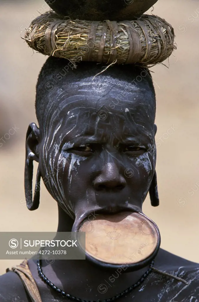A woman of the Mursi tribe.  Once married Mursi women pierce their lower lip and stretch it by inserting  increasingly large plugs until they can wear a clay lip plate.  The size of the lip plate reflects the bride price paid by their husband.  Within the Omo Valley, the Mursi have a reputation for being extremely fierce and aggressive but also for their skill at making pots.
