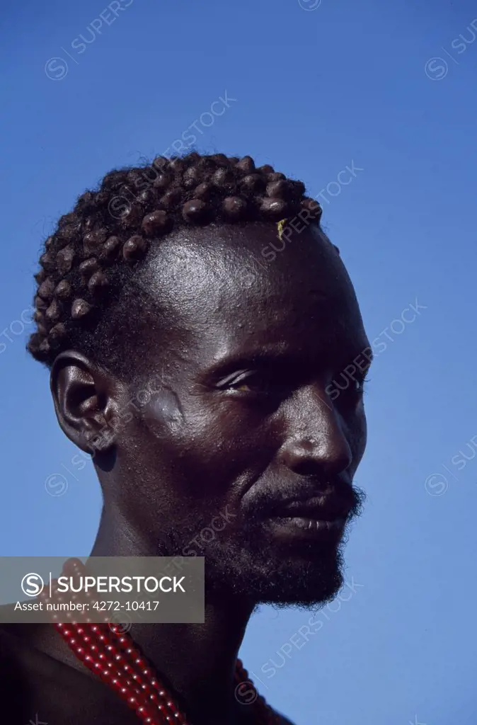 The distinctive hair style of this Dassanech man, achieved using a combination of clay, animal fat and ochre, signifies that he has killed a man recently.  In time he will make patterns of scars on his chest and shoulders as a lasting mark of his prowess in combat.