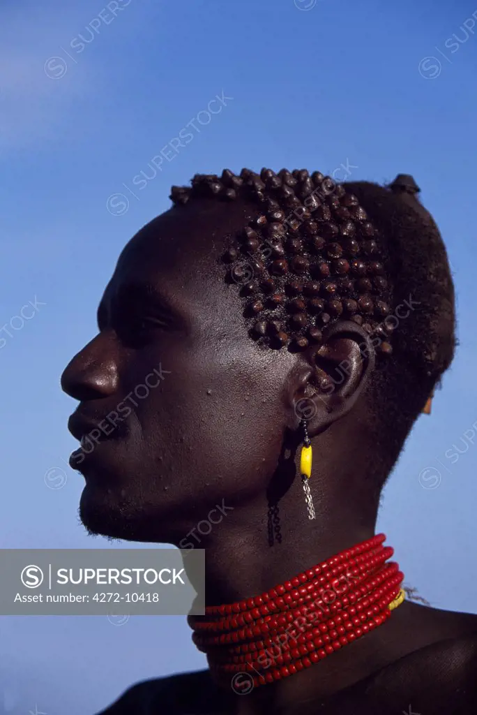 The distinctive hair style of this Dassanech man, achieved using a combination of clay, animal fat and ochre, signifies that he has killed a man recently.  In time he will make patterns of scars on his chest and shoulders as a lasting mark of his prowess in combat.  Much the largest of the tribes in the Omo Valley numbering around 50,000, the Dassanech (also known as the Galeb, Changila or Merille) are Nilotic pastoralists and agriculturalists.