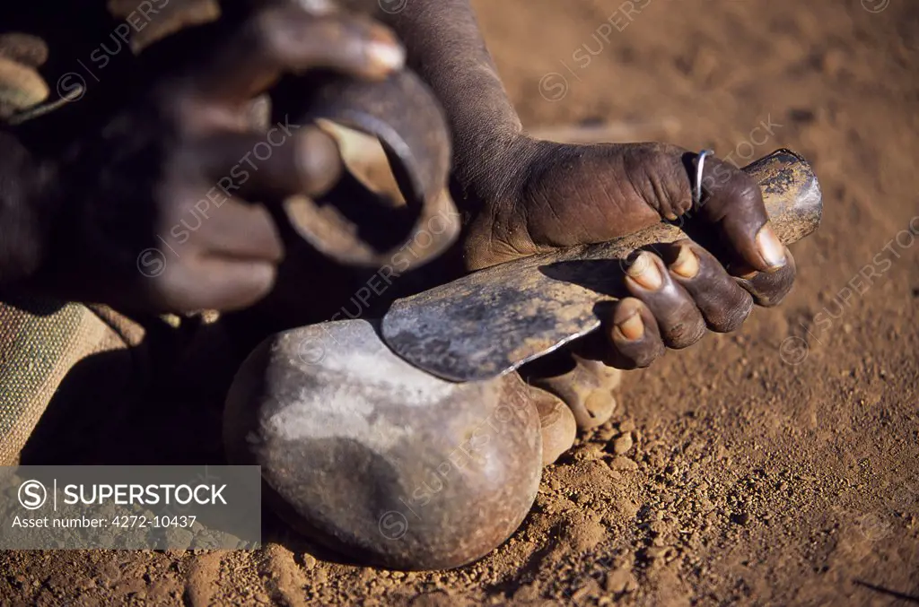 A  Dassanech man beats out the blade of a hand axe using a stone as an anvil and a piece of iron as a hammer.  Much the largest of the tribes in the Omo Valley numbering around 50,000, the Dassanech (also known as the Galeb, Changila or Merille) are Nilotic pastoralists and agriculturalists.