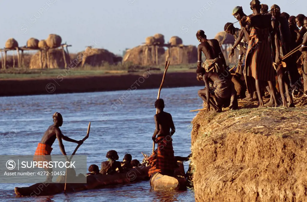 Dassanech tribesmen and women load into a dugout canoe ready to pole across the Omo River.  Much the largest of the tribes in the Omo Valley numbering around 50,000, the Dassanech (also known as the Galeb, Changila or Merille) are Nilotic pastoralists and agriculturalists.