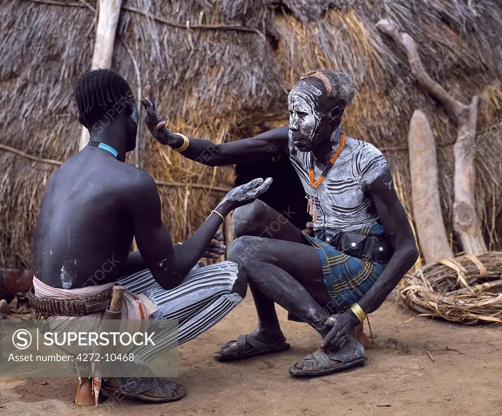 Karo men paint each other in preparation for a dance in the village of Duss.  A small Omotic tribe related to the Hamar, who live along the banks of the Omo River in southwestern Ethiopia, the Karo are renowned for their elaborate body painting using white chalk, crushed rock and other natural pigments.