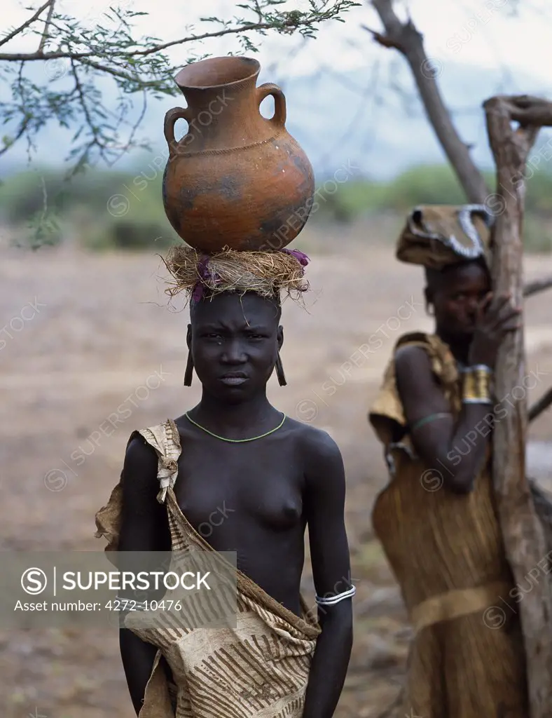 A Mursi girl stands with a clay pot on her head .  Within the Omo Valley, the Mursi have a reputation for being extremely fierce and aggressive.  They are also renowned for their skill at making clay pots.