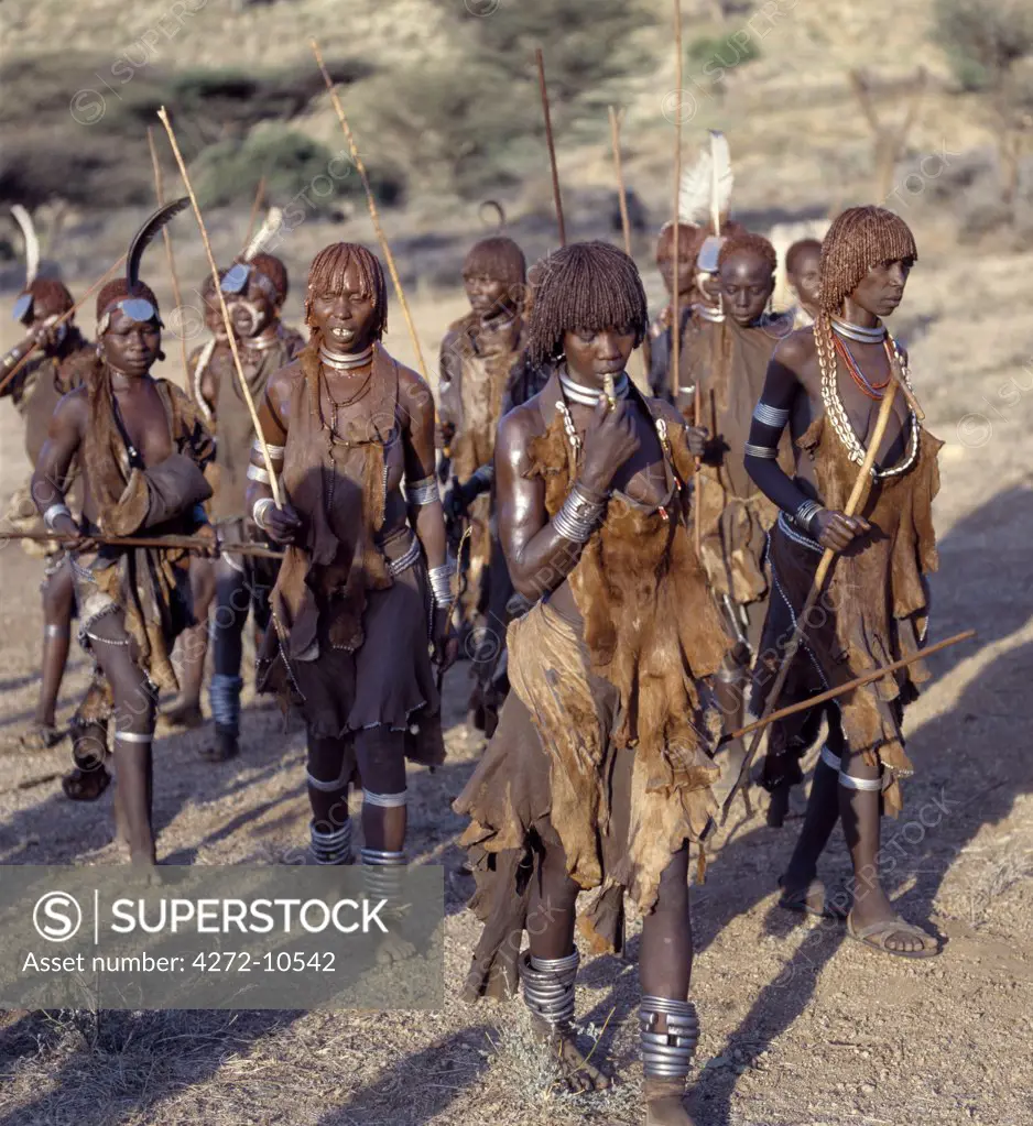 Hamar women dance, sing and blow small tin trumpets during a Jumping of the Bull ceremony. The semi nomadic Hamar of Southwest Ethiopia embrace an age grade system that includes several rites of passage for young men.