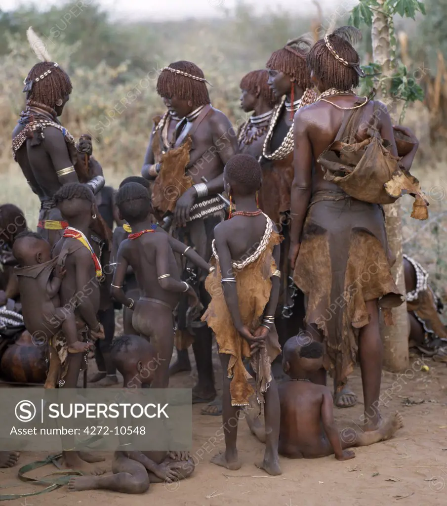 A group of Hamar women and children in traditional dress.The Hamar are semi nomadic pastoralists whose richly ochred women have striking styles of traditional dress.  Skins are widely used for clothing and cowrie shells are popular adornments yet the sea is 500 miles from their home.