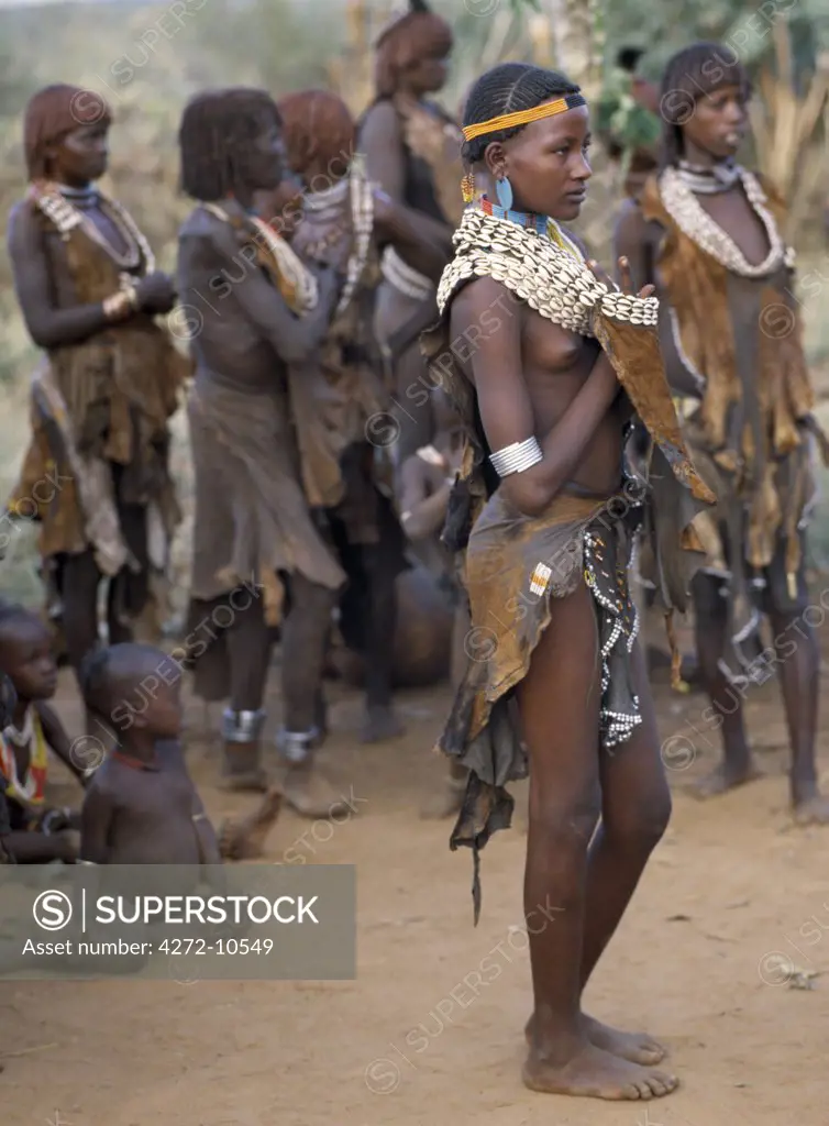 An attractive Hamar girl in traditional dress. The Hamar are semi nomadic pastoralists whose women have striking styles of traditional dress.  Skins are widely used for clothing and cowrie shells are popular adornments yet the sea is 500 miles from their home