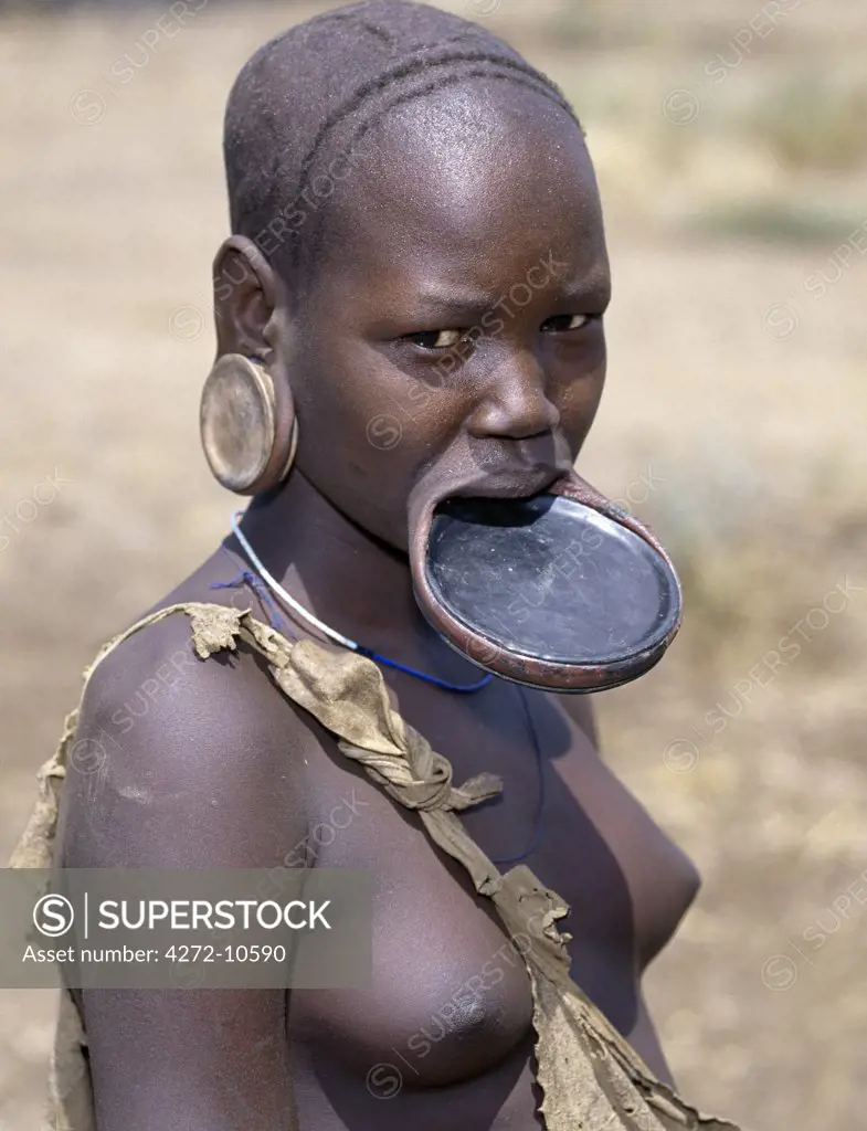 A Mursi woman wearing a large clay lip plate.  Shortly before marriage, a girls lower lip will be pierced and progressively stretched over a year or so.  The size of the lip plate often determines the quantum of the bride price.    The reason for this singular practice is not fully understood but Mursi women will claim that it enhances their beauty.