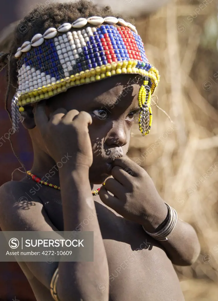 A Dassanech child wearing a broad headband decorated with glass beads and cowries.The Dassanech speak a language of Eastern Cushitic origin. They live in the Omo Delta and they practice animal husbandry and fishing as well as agriculture.