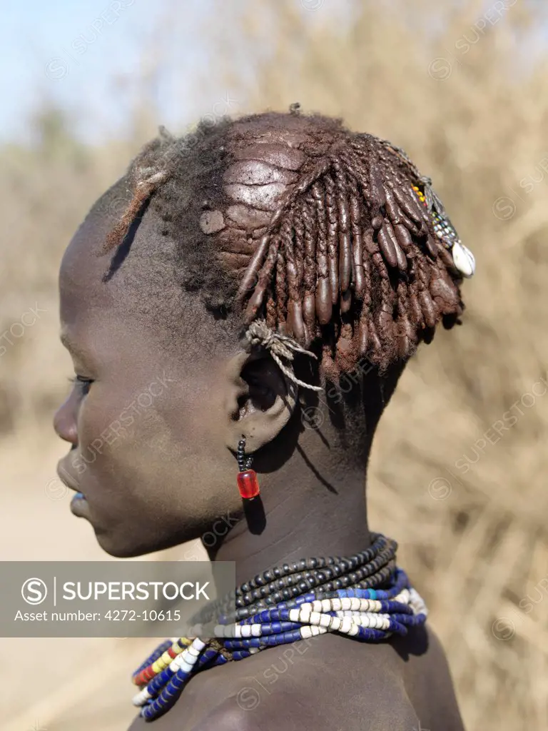 The braided and ochred hairstyle of a Dassanech girl, which has been embellished with beads and cowries.The Dassanech speak a language of Eastern Cushitic origin. They live in the Omo Delta and they practice animal husbandry and fishing as well as agriculture.