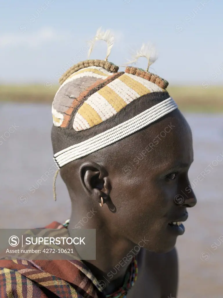 A finely decorated clay hairstyle of a young Dassanech man. The row of decorations on top of the head are ostrich feather holders, which are made from the pounded sinews of oxen intertwined with thin brass wire.The Omo Delta of southwest Ethiopia is one of the least accessible and least developed parts of East Africa.