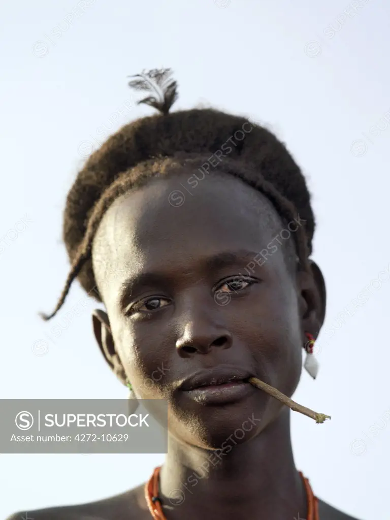 The braided hairstyle of a young Dassanech man.   The stick in his mouth is used a toothbrush to clean his teeth.The Omo Delta of southwest Ethiopia is one of the least accessible and least developed parts of East Africa. As such, the culture, social organization, customs and values of the people have changed less than elsewhere.