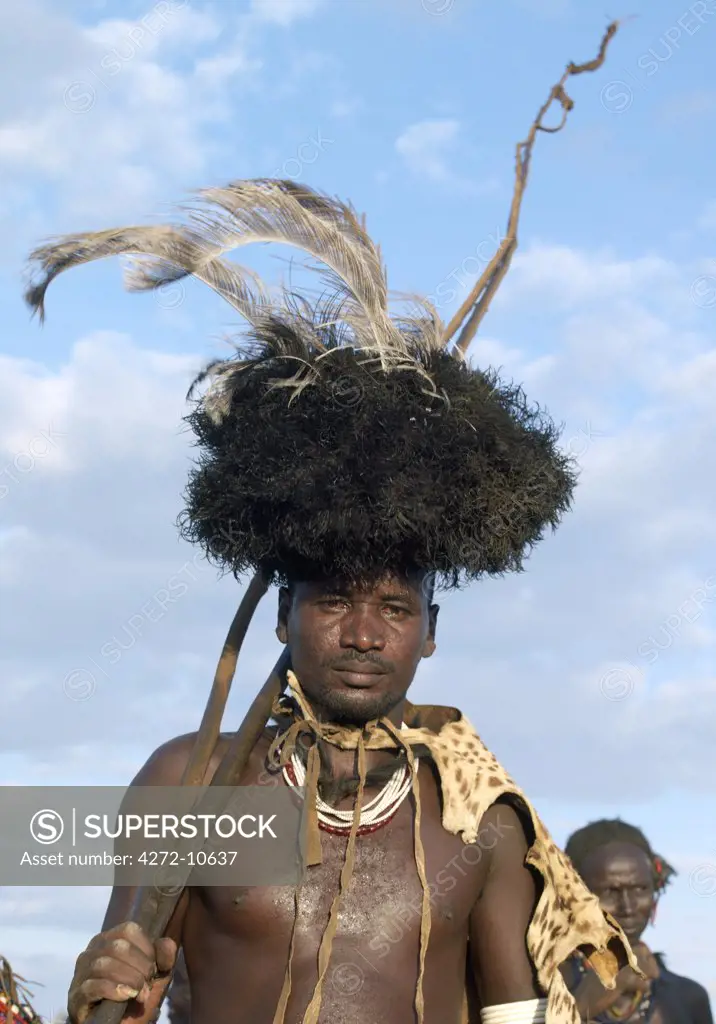 In the early morning, a Dassanech man puts on his serval cat skin cape and ostrich feather headdress to participate in his Dimi ceremony, an important initiation ceremony, which every male member of the tribe must undergo before their daughters are circumcised prior to marriage. The Dassanech speak a language of Eastern Cushitic origin.