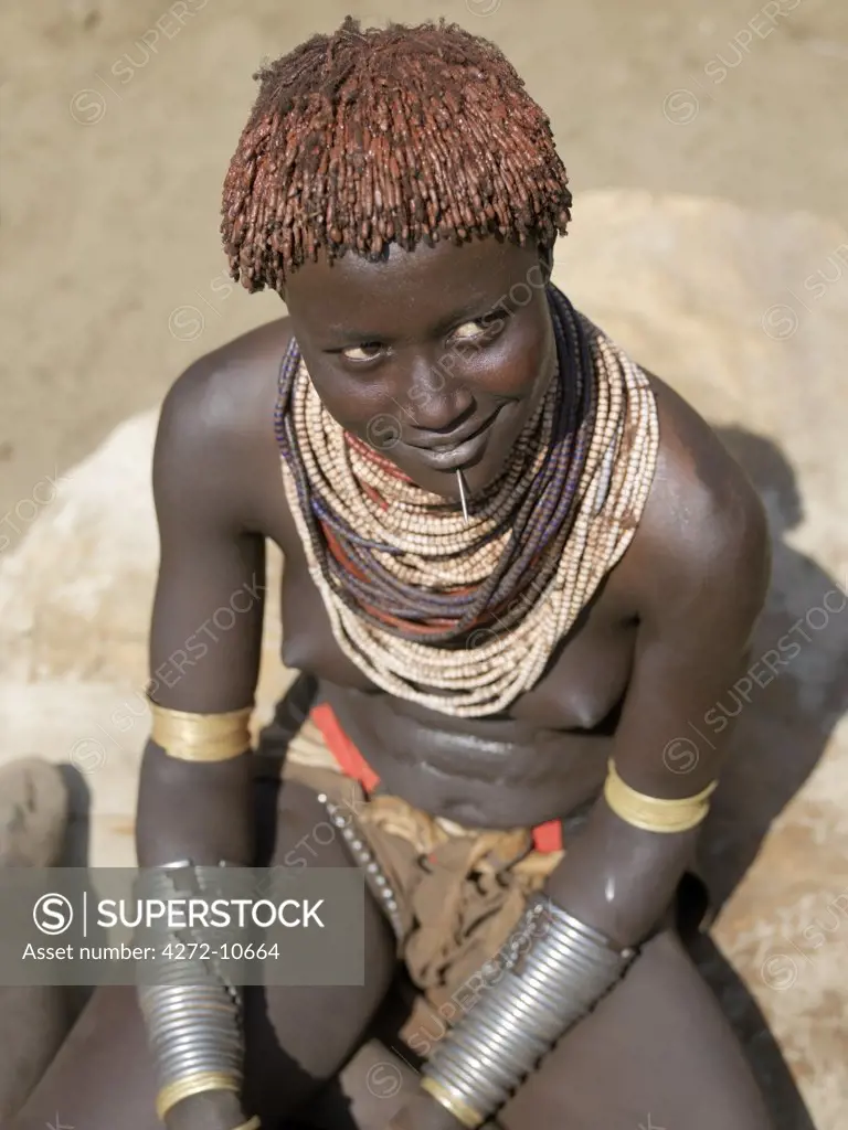 A Karo girl in all her finery.  It is a Karo tradition for girls and young women to pierce a hole below the lower lip in which they place a thin piece of metal or a nail for decoration. The Karo are a small tribe living in three main villages along the lower reaches of the Omo River in southwest Ethiopia.
