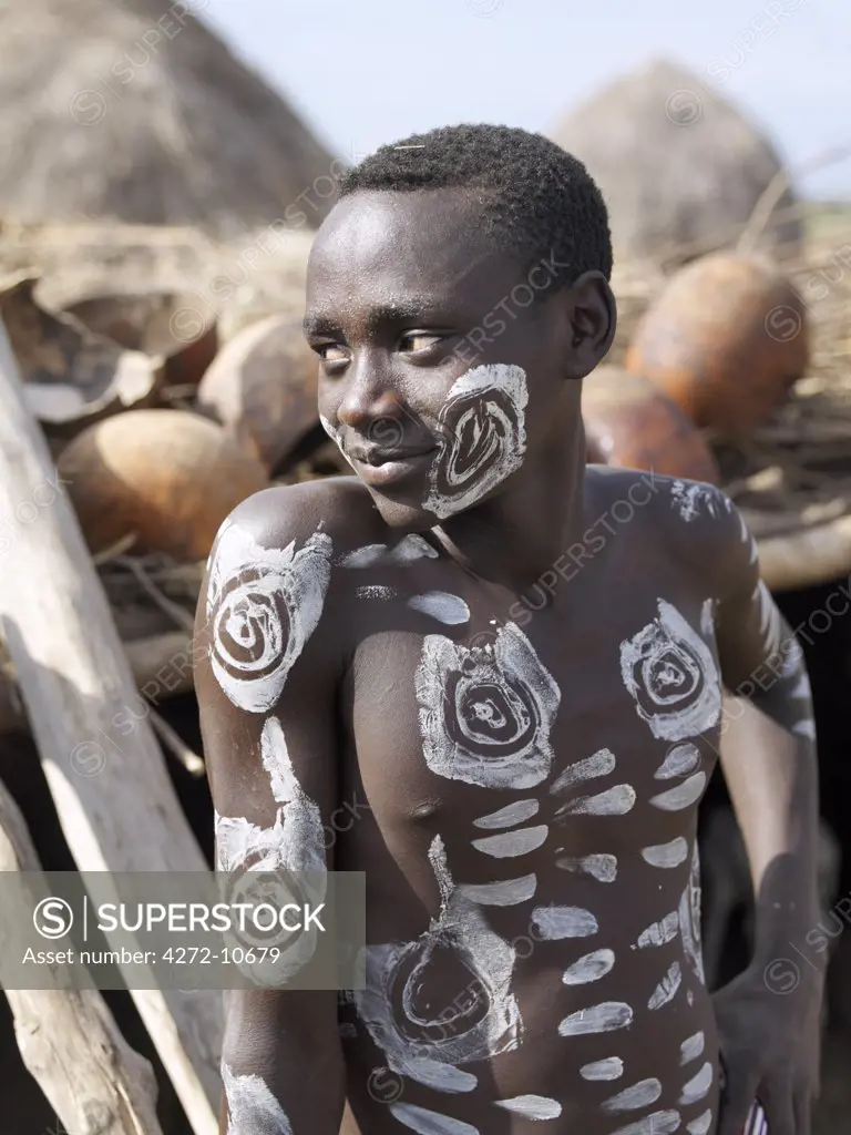 A young Kwegu man with his face and torso decorated with abstract symbols. The Kwegu (known to the Karo as Muguji  a degoratory name meaning Working Ant are the smallest tribe living on the banks the Omo River in southwest Ethiopia.