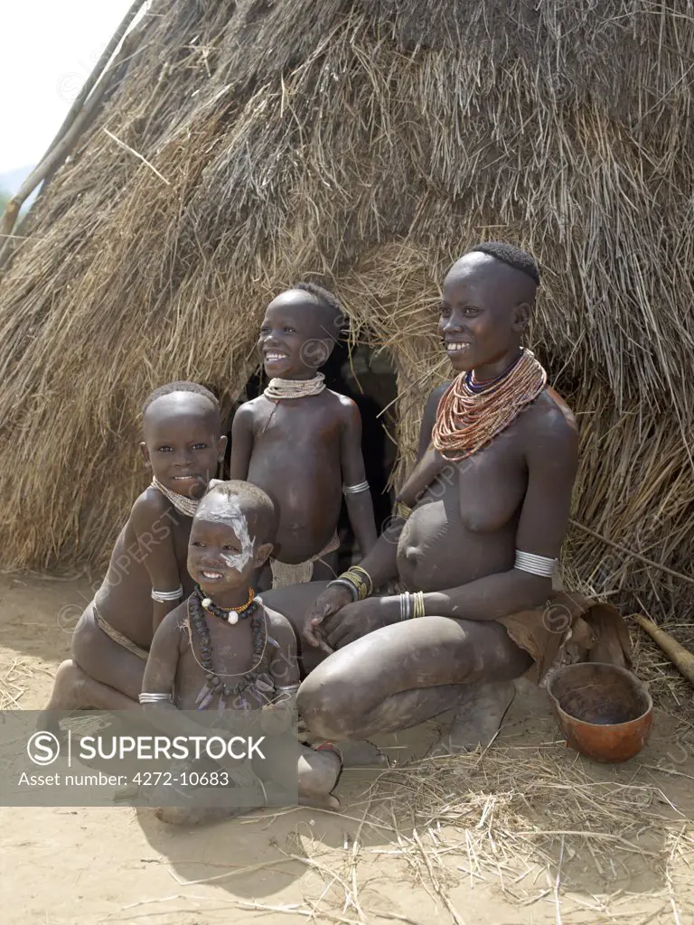 A Kwegu mother and her children outside their family home.  The Kwegu are the smallest tribe living on the banks the Omo River in southwest Ethiopia.