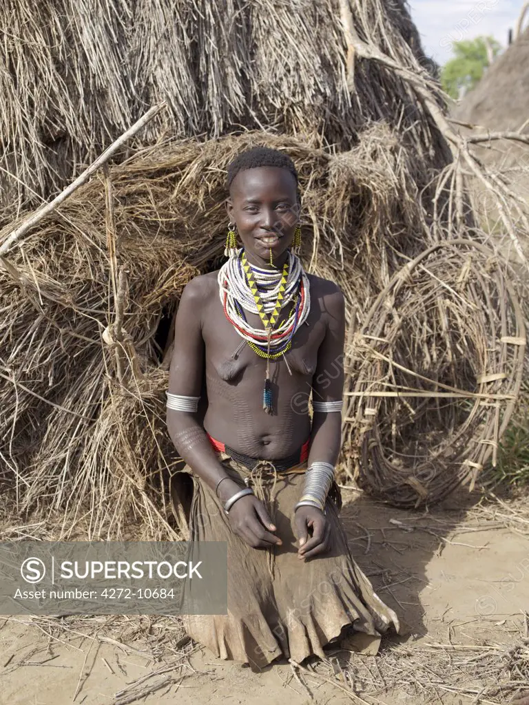 A Kwegu mother outside their family home. The Kwegu are the smallest tribe living on the banks the Omo River in southwest Ethiopia.