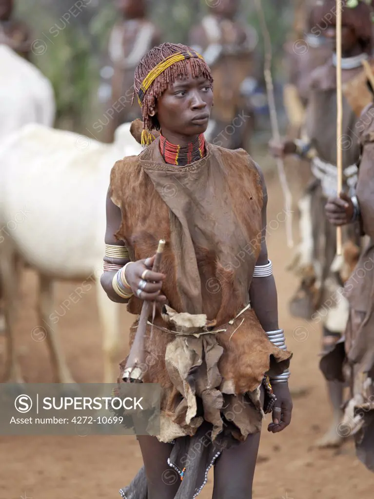 A Hamar woman holds a tin trumpet at a Jumping of the Bull ceremony. The Hamar are semi nomadic pastoralists of Southwest Ethiopia whose women wear striking traditional dress and style their red ochred hair mop fashion.