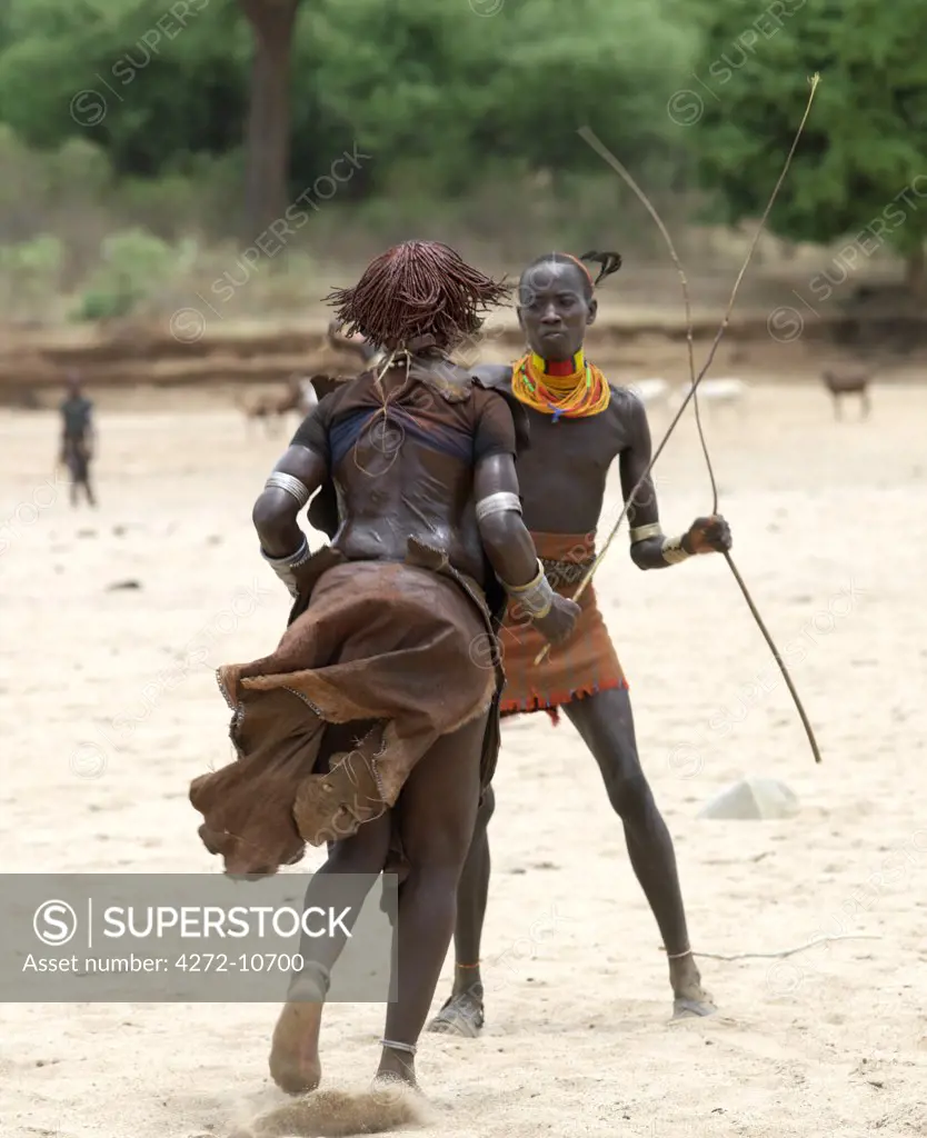A Hamar woman being whipped by a man at a Jumping of the Bull ceremony. The Hamar are semi nomadic pastoralists of Southwest Ethiopia whose women wear striking traditional dress and style their red ochred hair mop fashion.